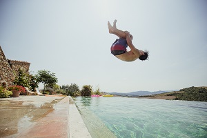 man backflipping into pool